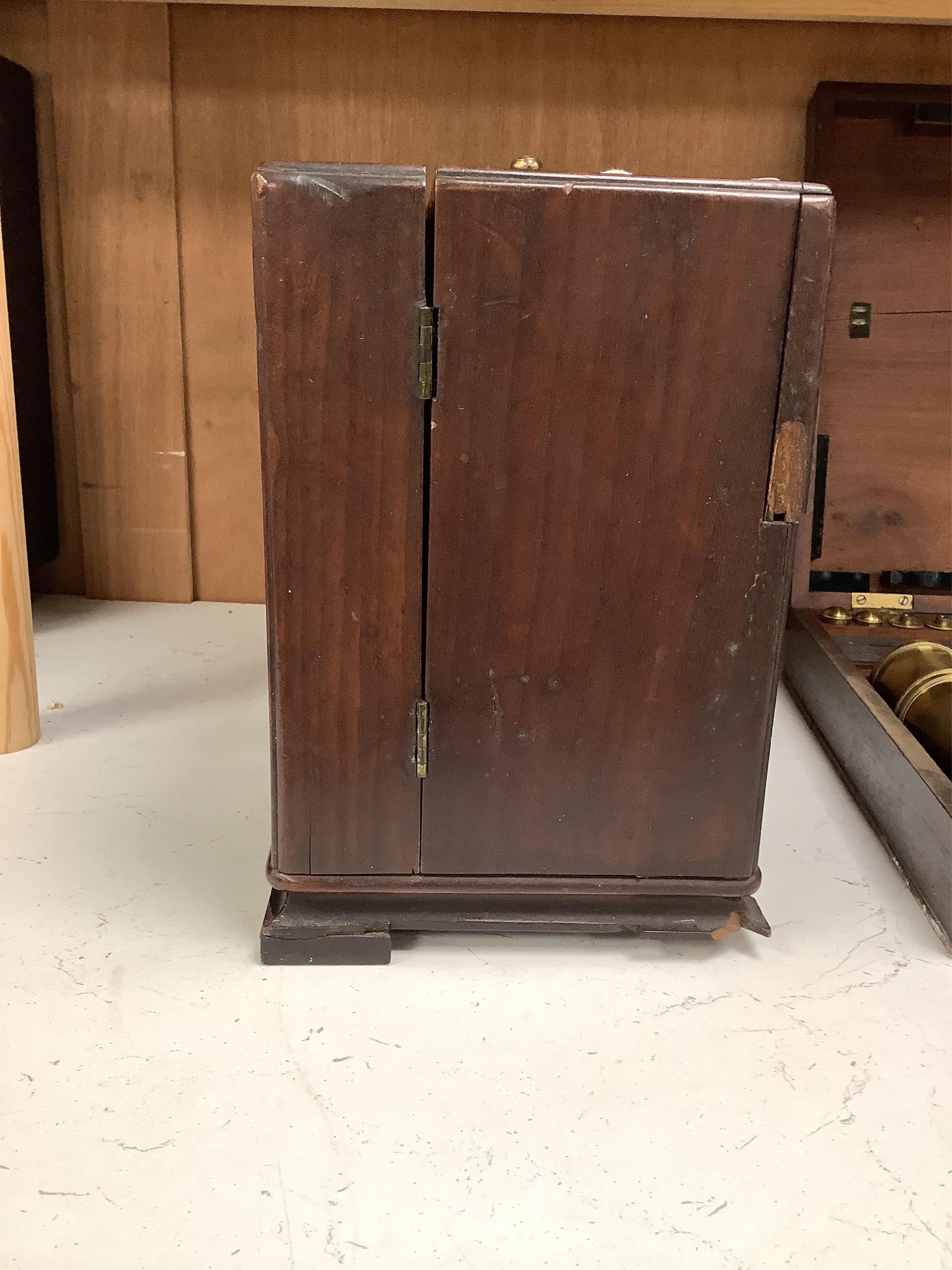 A 19th century mahogany apothecary cabinet, containing 20 bottles of various medicinal compounds and poisons, some sealed, all with paper labels, mainly for ‘C. Woollven, Operative & Dispensing Chemist, 108, High Street,